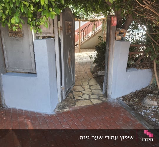שביל מרוצף עם שער פתוח ועצים מסביב